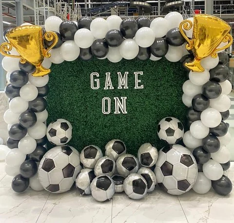 Greenery wall with a football theme and trophy balloons