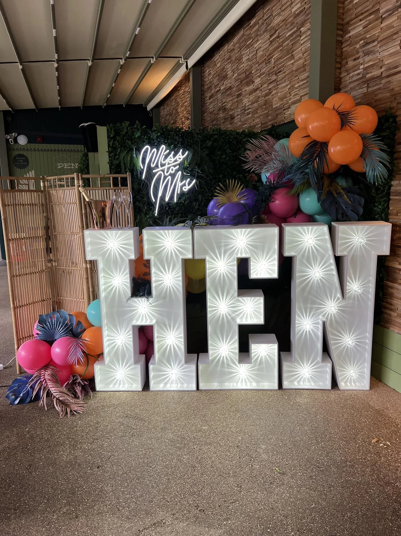 Light up letters with a neon sign and a greenery wall